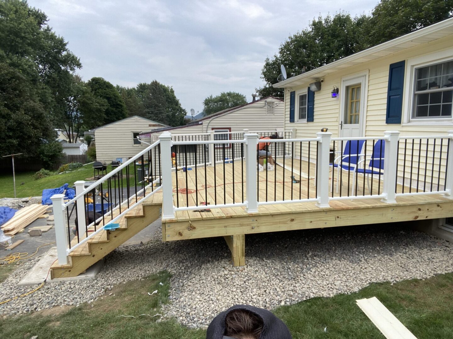 A deck with stairs and railing in the middle of a yard.