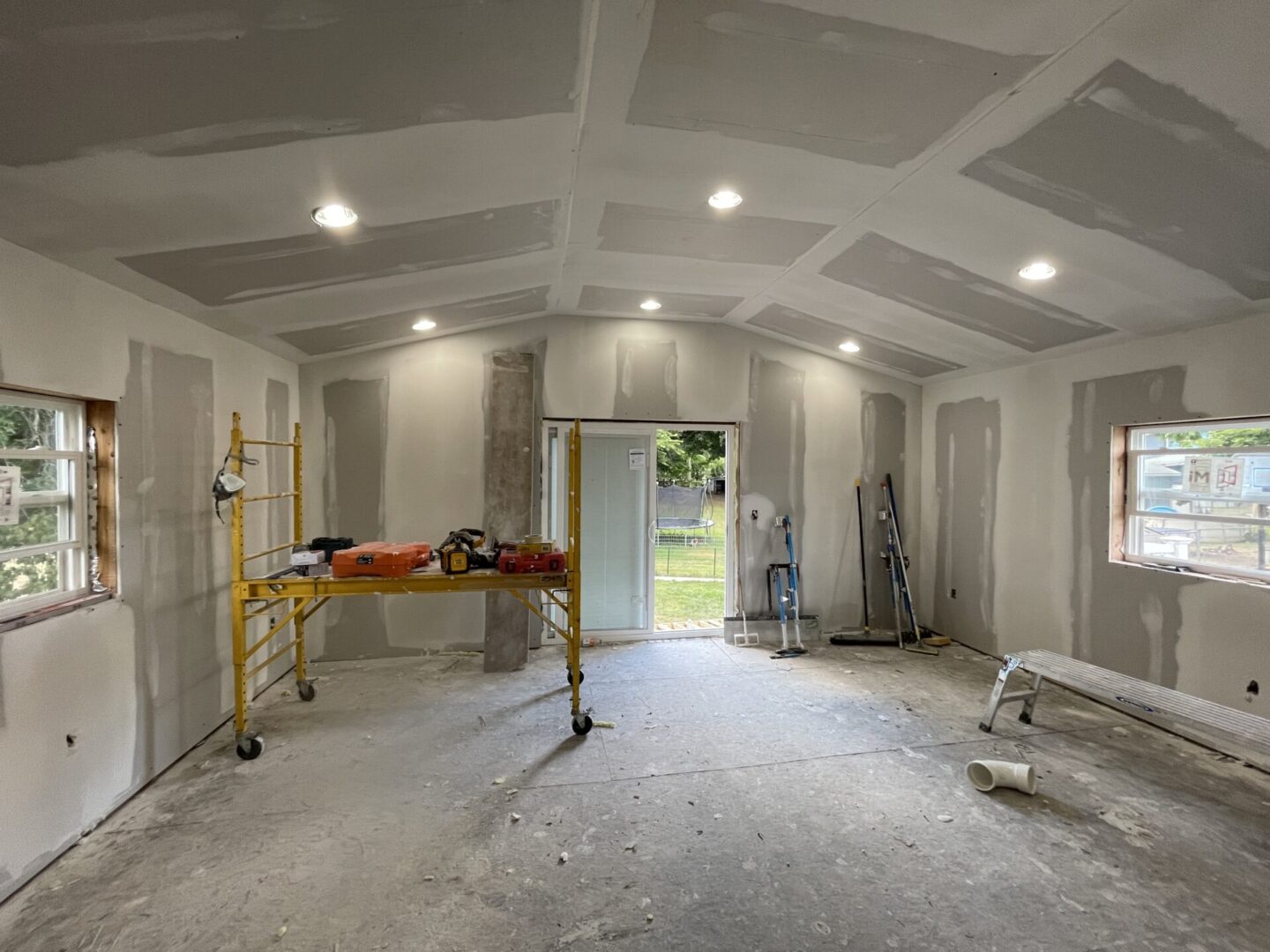 A room with walls being remodeled and the ceiling is being painted.