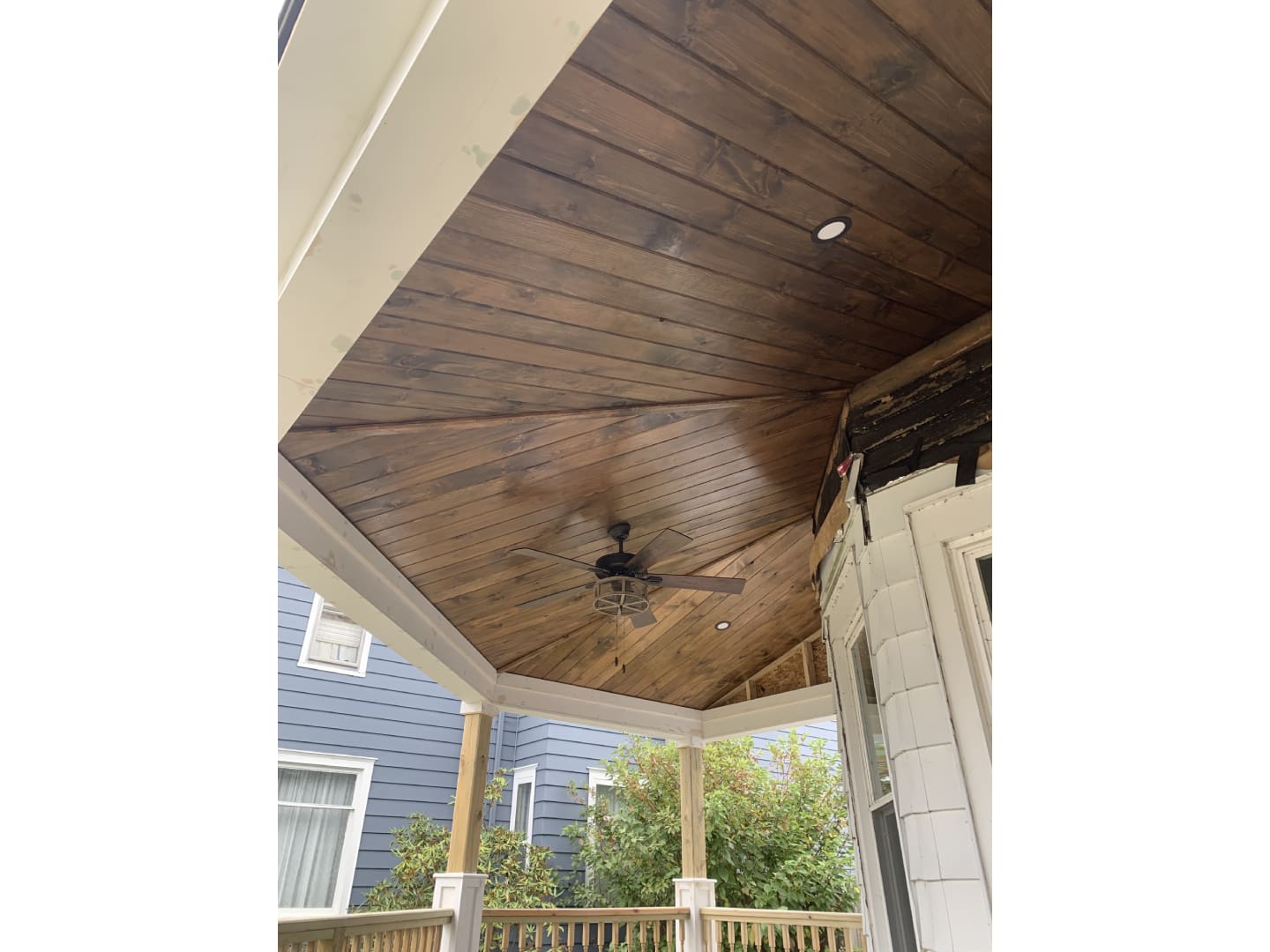 A ceiling fan is mounted to the side of a porch.